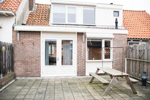 un banc en bois devant une maison en briques dans l'établissement huisje de Strandjutter, à Katwijk aan Zee
