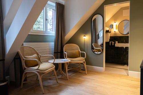uma casa de banho com 2 cadeiras, uma mesa e um lavatório. em Boutique Hotel Waldhaus beider Basel em Basileia