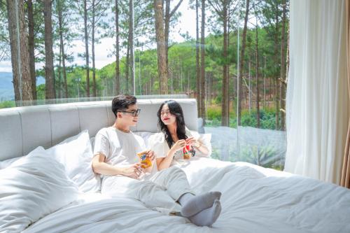 a man and a woman sitting on a bed at Omirita Resort Dalat in Da Lat