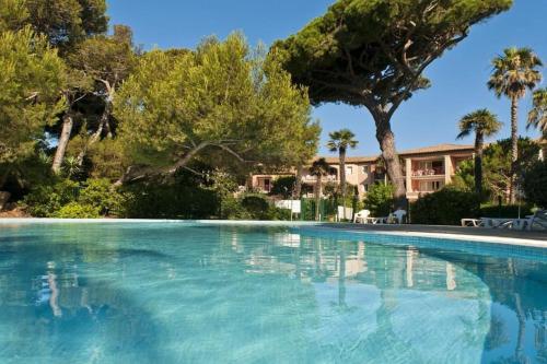 une grande piscine avec des arbres et une maison dans l'établissement Superbe appartement 50M de la plage en bord de mer, à Hyères