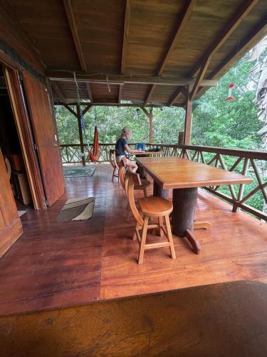 a woman sitting at a table on the deck of a house at Caoni riverside Lodge in Puerto Quito