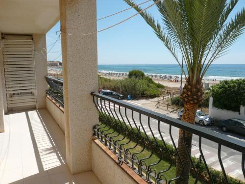 a balcony with a palm tree and a view of the beach at PLAYAMAR ORANGE COSTA 3 dormitorios in Alcossebre