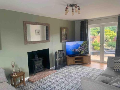 a living room with a flat screen tv and a fireplace at Holly Tree Cottage in Barmby on the Moor