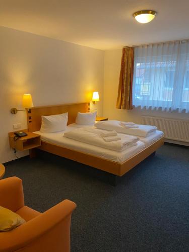 a bedroom with a large bed and a chair at Hotel Sonne in Stupferich