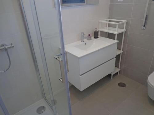 a white bathroom with a sink and a shower at Villa met het rustige strand van Salgado op wandelafstand in São Martinho do Porto