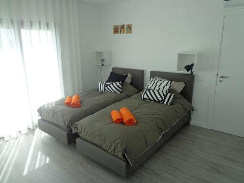 two beds with orange pillows in a living room at Villa met het rustige strand van Salgado op wandelafstand in São Martinho do Porto