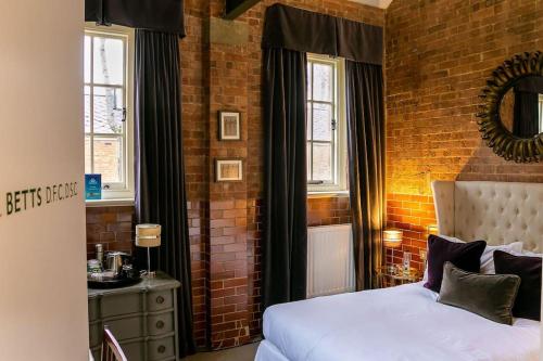 a bedroom with a bed and a brick wall at Betts (Private Ensuite room) at Bicester Heritage in Bicester