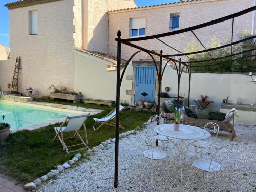 a patio with a table and chairs next to a pool at Maison 1823 - Suites de charme à Garons in Garons