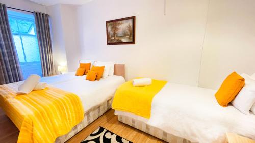 two beds in a room with yellow and white at Catcune Suite in Gorebridge
