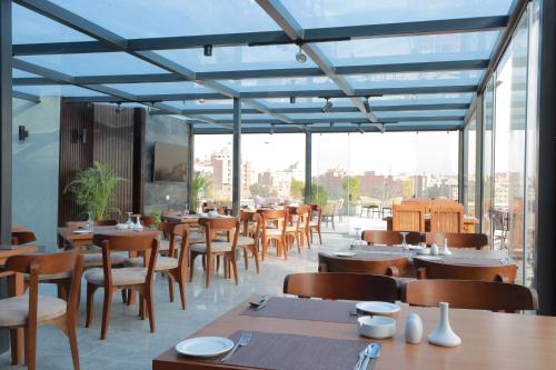 um restaurante com mesas e cadeiras de madeira e janelas em Pyramid Front Hotel no Cairo