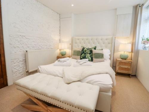 a white bedroom with two beds and a bench at Primrose in Blandford Forum