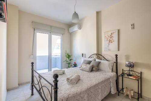 ein Schlafzimmer mit einem Bett und einem großen Fenster in der Unterkunft Maria's Cozy Apartment in Heraklion in Iraklio