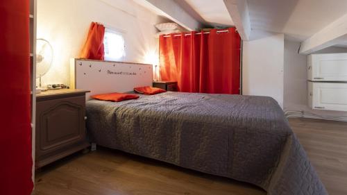 - une chambre avec un lit et des rideaux rouges dans l'établissement Les Estivales- 9H- Studio charme- 4 pers, au Cap d'Agde