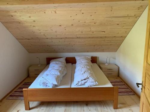 a bed in a room with a wooden ceiling at Haus Stelz in Nesslau