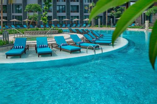 a row of blue lounge chairs next to a swimming pool at Courtyard by Marriott Bali Nusa Dua Resort in Nusa Dua