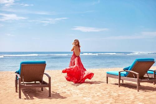 a woman in a red dress walking on the beach at Courtyard by Marriott Bali Nusa Dua Resort in Nusa Dua