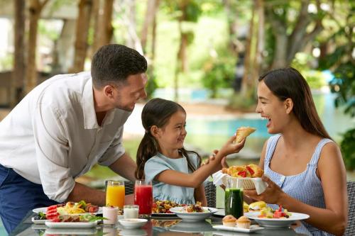 a family sitting at a table eating food at Courtyard by Marriott Bali Nusa Dua Resort in Nusa Dua