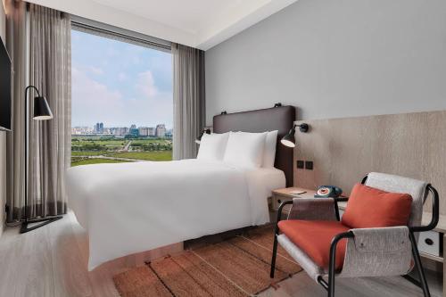 a hotel room with a large bed and a window at Moxy Taichung in Taichung