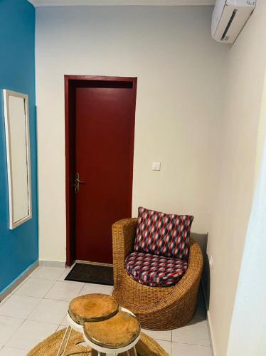 a room with a chair and two tables and a door at Résidence Karamel Yaoundé Anguissa in Yaoundé