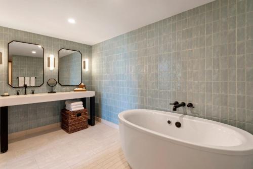La salle de bains est pourvue d'une baignoire, d'un lavabo et d'un miroir. dans l'établissement Merriweather Lakehouse Hotel, Autograph Collection, à Columbia
