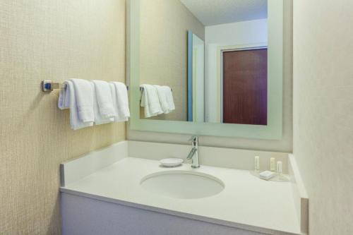a bathroom with a sink with a mirror and towels at SpringHill Suites Minneapolis West St. Louis Park in Saint Louis Park