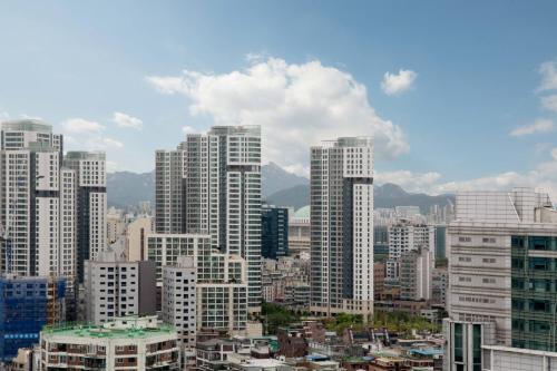 um horizonte da cidade com edifícios altos e montanhas em Courtyard By Marriott Seoul Times Square em Seul