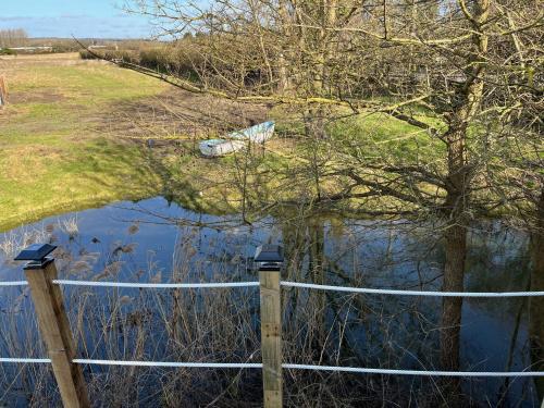 a fence next to a body of water with a tree at Rife Lodges in Arundel