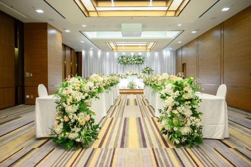 a row of tables with white and pink flowers at Courtyard By Marriott Seoul Times Square in Seoul