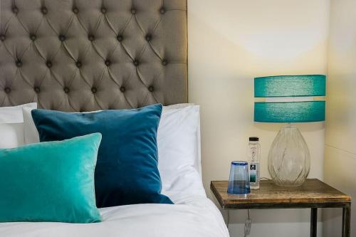 uma cama com almofadas azuis e um candeeiro sobre uma mesa em Bowen-Buscarlet (Large Suite) at Bicester Heritage em Bicester