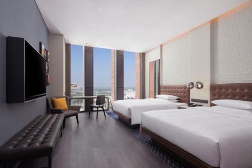 Four Points by Sheraton Tianjin National Convention and Exhibition Center في تيانجين: غرفة فندقية بسريرين وتلفزيون بشاشة مسطحة