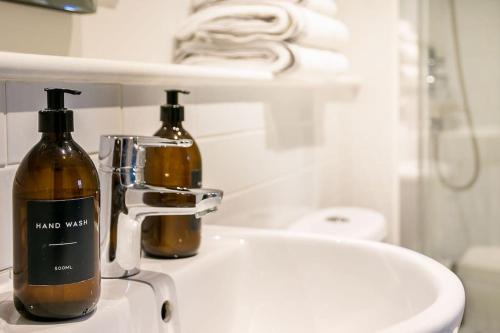 Un baño con lavabo con dos botellas. en Bowen-Buscarlet (Large Suite) at Bicester Heritage en Bicester