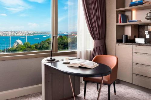a room with a desk and a window with a table and a chair at The Ritz-Carlton, Istanbul at the Bosphorus in Istanbul