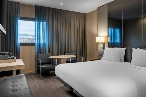 AC Hotel Sants, a Marriott Lifestyle Hotel في برشلونة: غرفة فندقية بسرير كبير وطاولة وكرسي