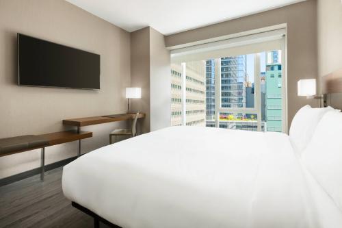 um quarto de hotel com uma grande cama branca e uma janela em AC Hotel by Marriott New York Times Square em Nova York