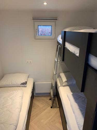 a small room with two bunk beds and a window at Vogelvrij, vakantie woningen met geheel omheinde tuin in Burgerbrug