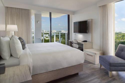 um quarto com uma cama, uma secretária e uma televisão em Courtyard Miami Coconut Grove em Miami
