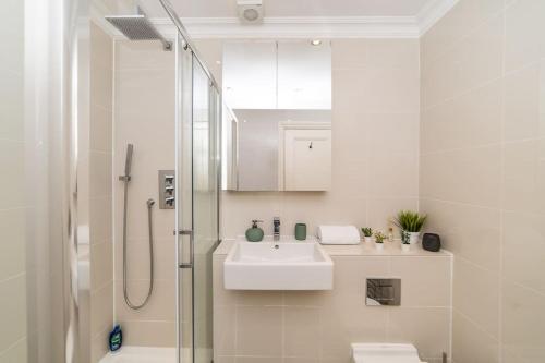 a white bathroom with a sink and a shower at [Covent Garden-British Museum] Apartment London in London