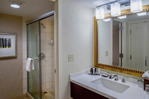 a bathroom with a sink and a shower with a mirror at Marriott St. Louis West in Chesterfield