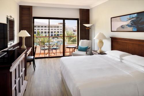 a hotel room with a large bed and a balcony at Dead Sea Marriott Resort & Spa in Sowayma