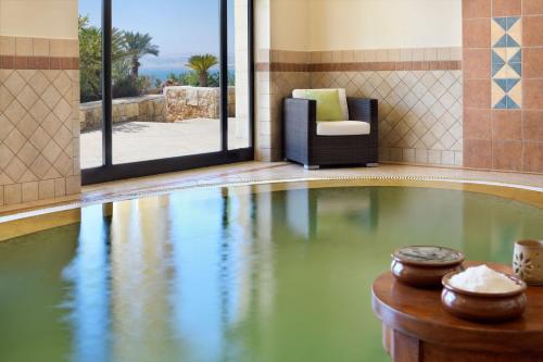 a swimming pool with a chair in a room with at Dead Sea Marriott Resort & Spa in Sowayma