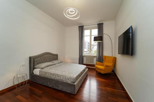 ein Schlafzimmer mit einem Bett, einem TV und einem Stuhl in der Unterkunft Appartamento esclusivo fronte lago, in centro a Como con garage in Como