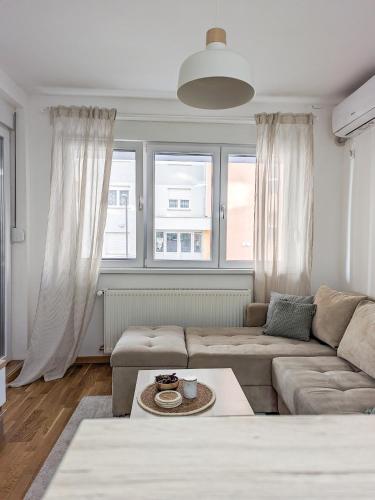 a living room with a couch and two windows at Apartman Una in Kragujevac