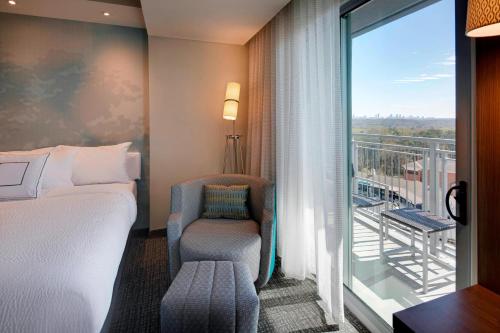 a bedroom with a bed and a chair and a balcony at Courtyard by Marriott Atlanta Vinings/Galleria in Atlanta