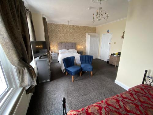 a bedroom with a bed and two blue chairs at Atlanta Guest House in Eastbourne