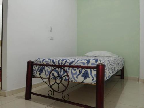 a small bed with a blue and white blanket on it at Guayacan Hostel in Cali
