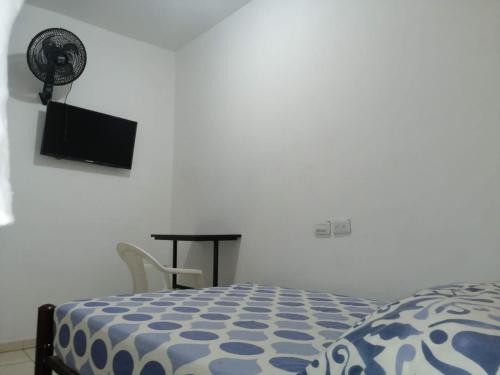 a bedroom with a bed and a television and a table at Guayacan Hostel in Cali