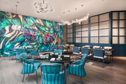 a dining room with tables and chairs and a mural at W Changsha in Changsha