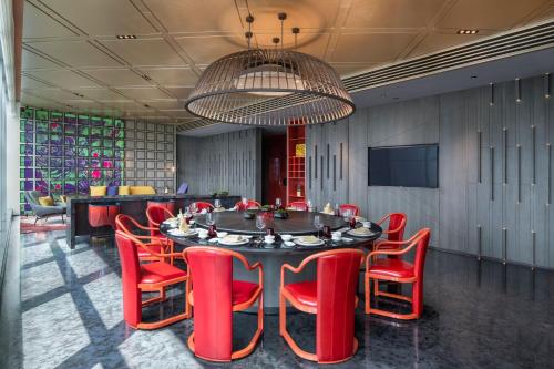 a dining room with a table and red chairs at W Changsha in Changsha