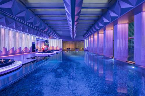 a swimming pool in a hotel with purple lighting at W Changsha in Changsha