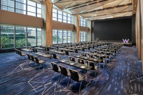 a large room with tables and chairs in front of a screen at W Changsha in Changsha